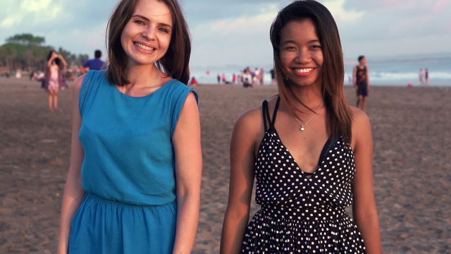 Portrait of two pretty girlfriends flirting to camera on beach, slow motion shot at 240fps
