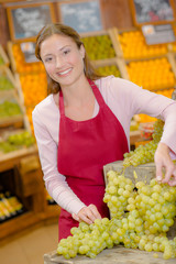 Shop assisitant stacking grapes