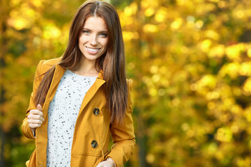 Beautiful elegant woman standing in a park in autumn