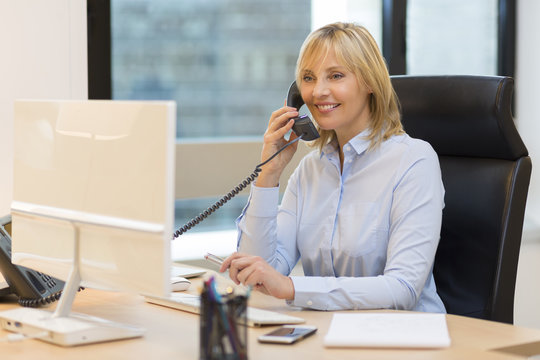 Middle aged business woman using phone at office