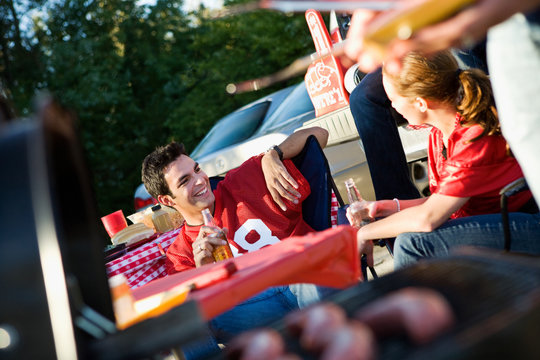 Tailgating: Man Talking To Friend While Waiting For Party Food
