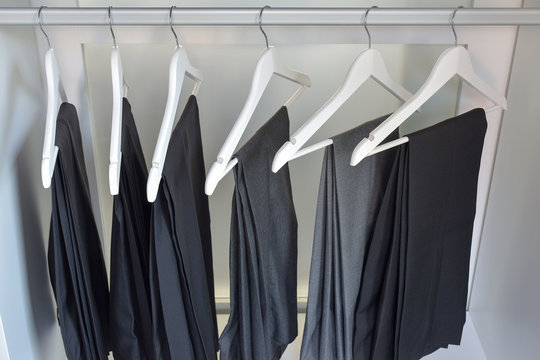 row of gray and black pants hangs in wardrobe at home