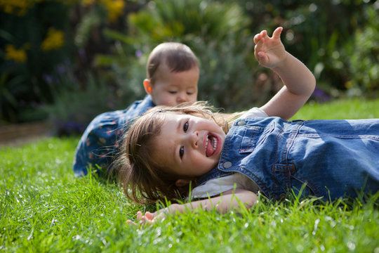 Toddler girl playing in the garden with her baby sister, selective focus