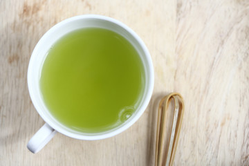 healthy green tea in cup on woodden background