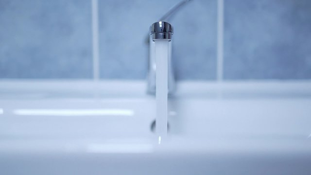 Cropped hand opening faucet in domestic bathroom. Lockdown footage of running water at home.
