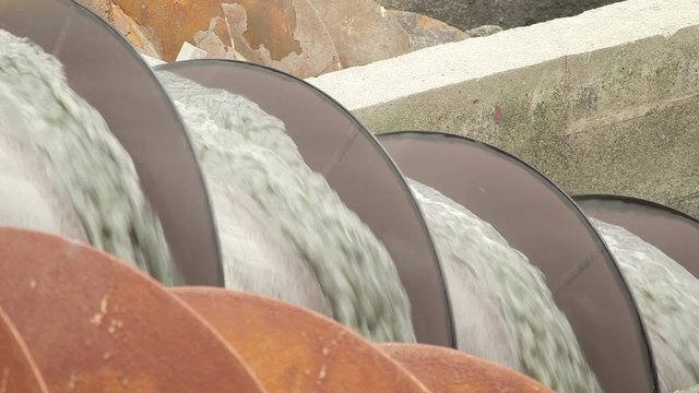 Close-up footage of water being processed in hydro screw. Detail shot of machinery in motion at hydroelectric power station.