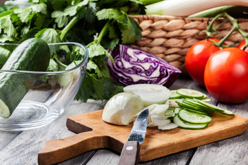 Chopped vegetables: onion and cucumber on cutting board