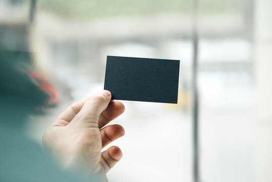 Male hand holding black business card on the window background