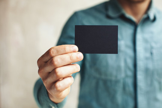 Man holding black business card on concrete wall background
