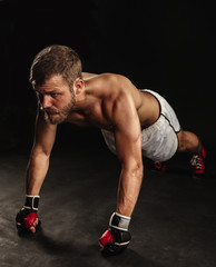 Athletic bearded boxer with gloves on a dark background