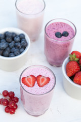 Three small glasses of smoothie on the white table in the garden