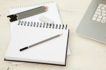 Two sketchpads, pencils and eraser on the white wooden table