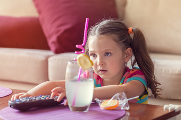 cute little girl with remote changes channel on tv