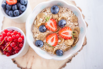 Breakfast: oatmeal cereals with berries on the white wooden table, selective focus