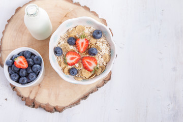 Breakfast: oatmeal cereals with berries on the white wooden table, selective focus