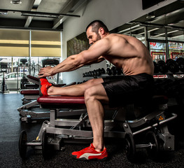 Fototapeta na wymiar Shirtless bodybuilder doing exercises in a gym.