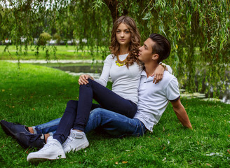 Man with woman relaxing on green grass in a park.