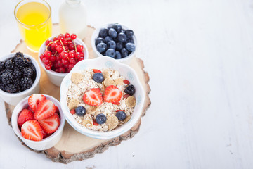 Breakfast: oatmeal cereals with berries on the white wooden table, selective focus