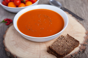 Tomato soup with dried herbs, chilli, tomoatoes and cream on the dark wooden table