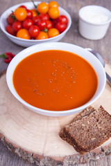 Tomato soup with dried herbs, chilli, tomoatoes and cream on the dark wooden table
