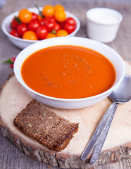 Tomato soup with dried herbs, chilli, tomoatoes and cream on the dark wooden table