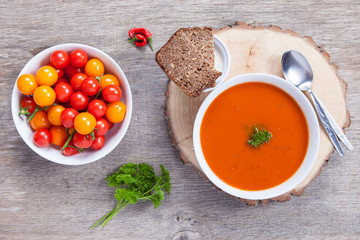 Tomato soup with frresh herbs, chilli, tomatoes and cream on the dark wooden table