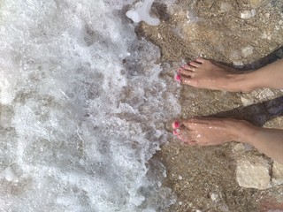 Girl feet on beach and sea wave