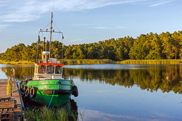 Landscape with a boat moored at the wooden pier near Kalmar, Sweden. - obrazy, fototapety, plakaty