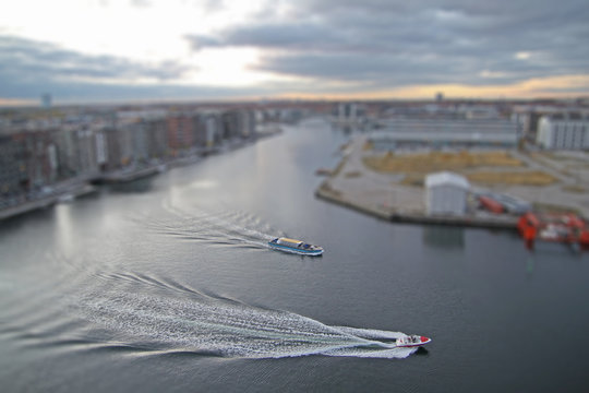 Wide canal in Copenhagen South area, Denmark, with speed boat and tour boat with miniature effect