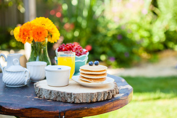 Breakfast in the garden: pancakes with yoghurt and berries on a rustic table