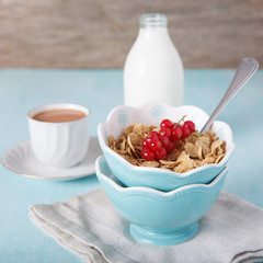 Cereals in the blue bowl with milk and coffee on the background