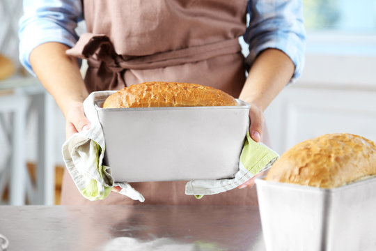 Baker checking freshly baked bread in kitchen of bakery