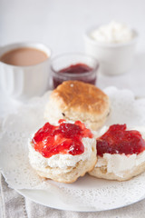 Scones with clotted cream and strawberry jam with tea on the white table