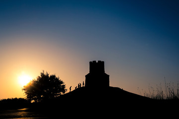 Obraz premium Sunset silhouettes of a medieval church on a hill, tree and peop