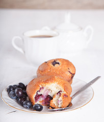 Two blueberry muffins on the white  table