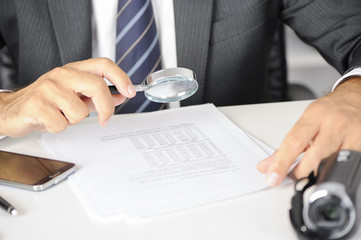 Businessman with magnifying glass reading documents