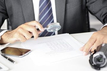 Businessman with magnifying glass reading documents