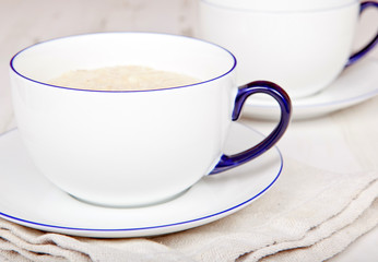 Porridge in breakfast cup on a white wooden table