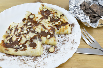 Triangular sweet pancakes covered with chocolate and hazelnuts