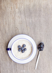 Porridge in breakfast cup on a  wooden table
