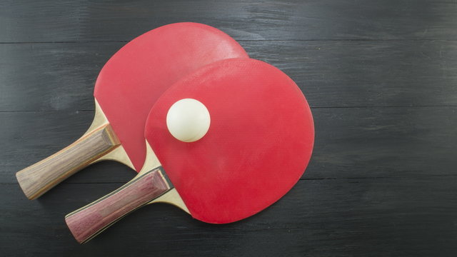 Two red table tennis rackets on dark background with copyspace