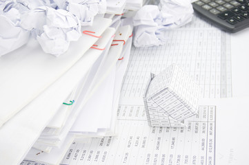 Bankruptcy of house and paper ball with stack of paperwork