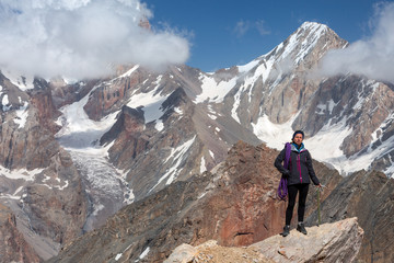 Fototapeta premium Female Climber Holding Ice Axe and Alpine Rope Full Body Portrait of Smiling Woman Staying on Pointed Rock Top Sporty Clothing High Altitude Mountain Landscape Blue Sky