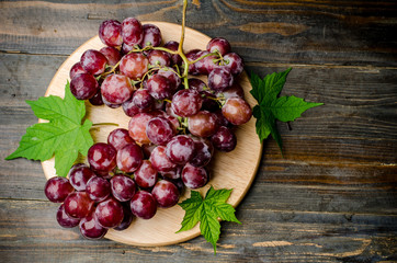 Red grape on wooden plate
