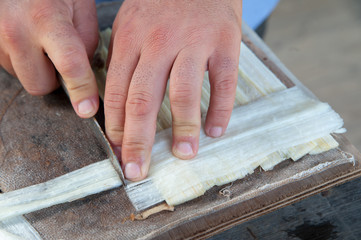 The working of Papyrus in Syracuse: an artisan is superimposing perpendicular thin strips obtained fom the stem of the plant to make a new leaf