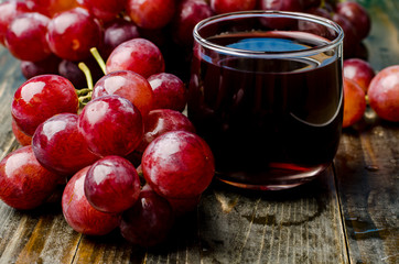 Red grape and juice on wooden background