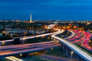 Washington DC stadsgezicht in de schemering met spitsuur verkeerspaden op de I-395 snelweg. Washington Monument, verlicht, domineert de skyline.