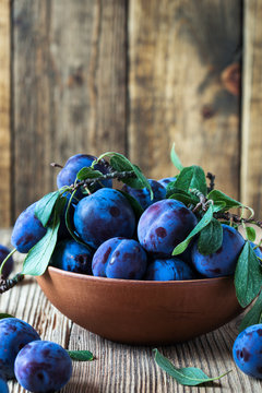 Fresh organic plums on  rustic wooden table