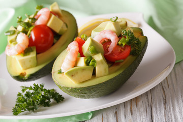 Avocado stuffed with shrimp close-up on a plate. horizontal
