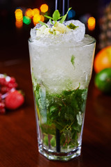 bright mojito cocktail on a table in the restaurant with the decor of ice and apple slices with bright backgrounds of beautiful disco lights. soft focus